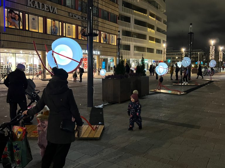 Ihmisiä valotaideteosten äärellä kävelykadulla.