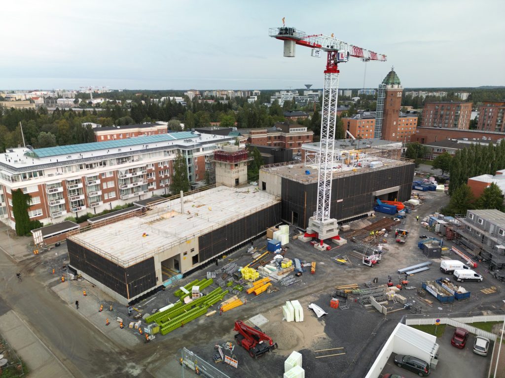 Ilmasta otettu valokuva, jossa nähdään suuri rakennustyömaa vanhojen punatiilisten rakennusten läheisyydessä.